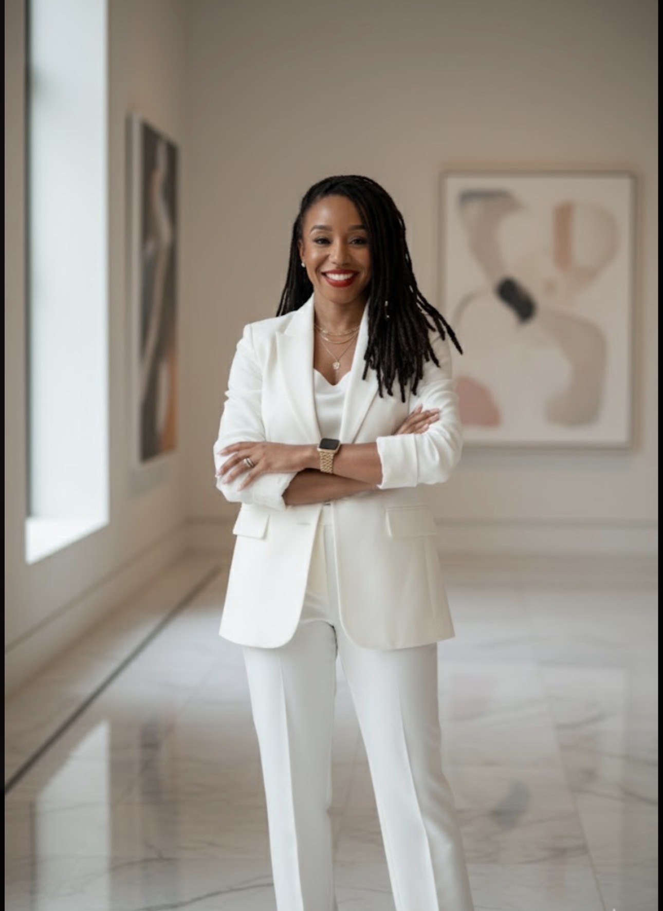 Tierra Banks in a white suit, arms crossed, in a gallery
